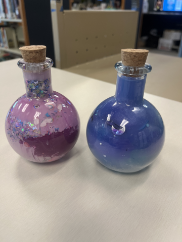 Two small potion jars that are used to create "galaxy" jars using paint, glitter, and cotton balls.