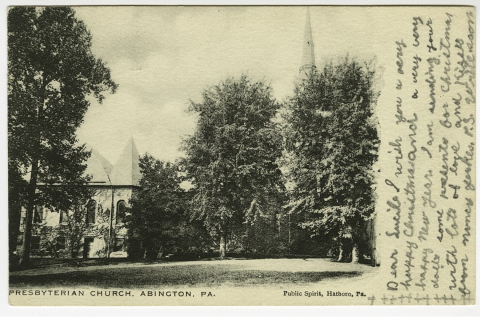 Old sepia toned postcard image of church with steeple hidden behind tall trees. Handwriting on right side of image