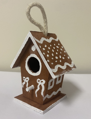 Wooden birdhouse painted to resemble a gingerbread house