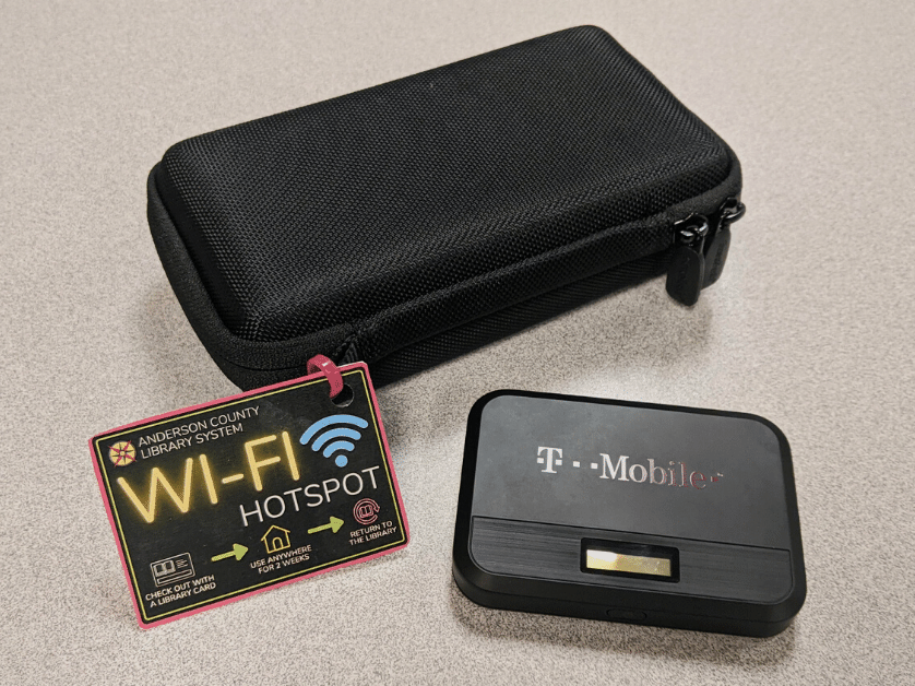 A T-Mobile Wi-Fi hotspot next to a case with a tag on it